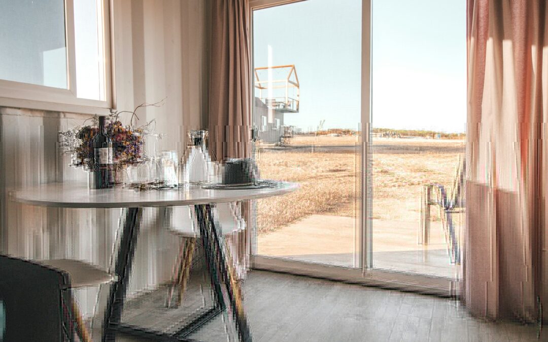 wine bottle near glass on end table beside closed window